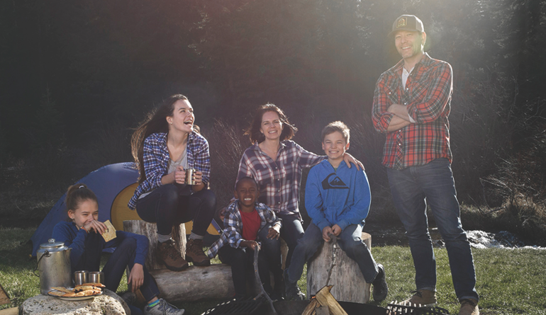 Aaron and Tina Neiman with their family outdoors around a campfire
