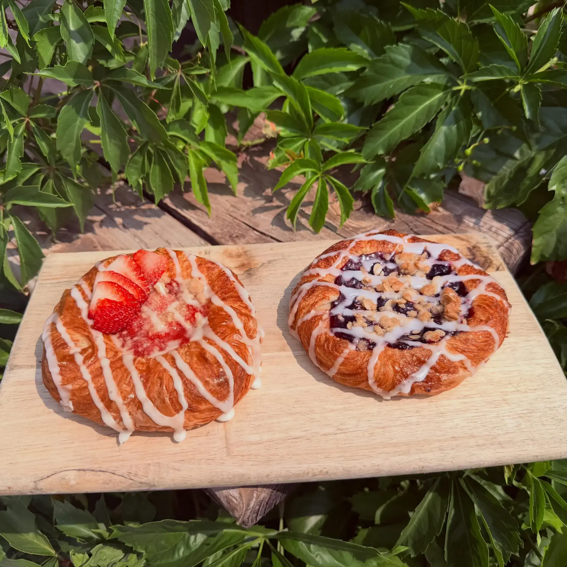 Strawberry and blueberry danishes with icing on a wooden board