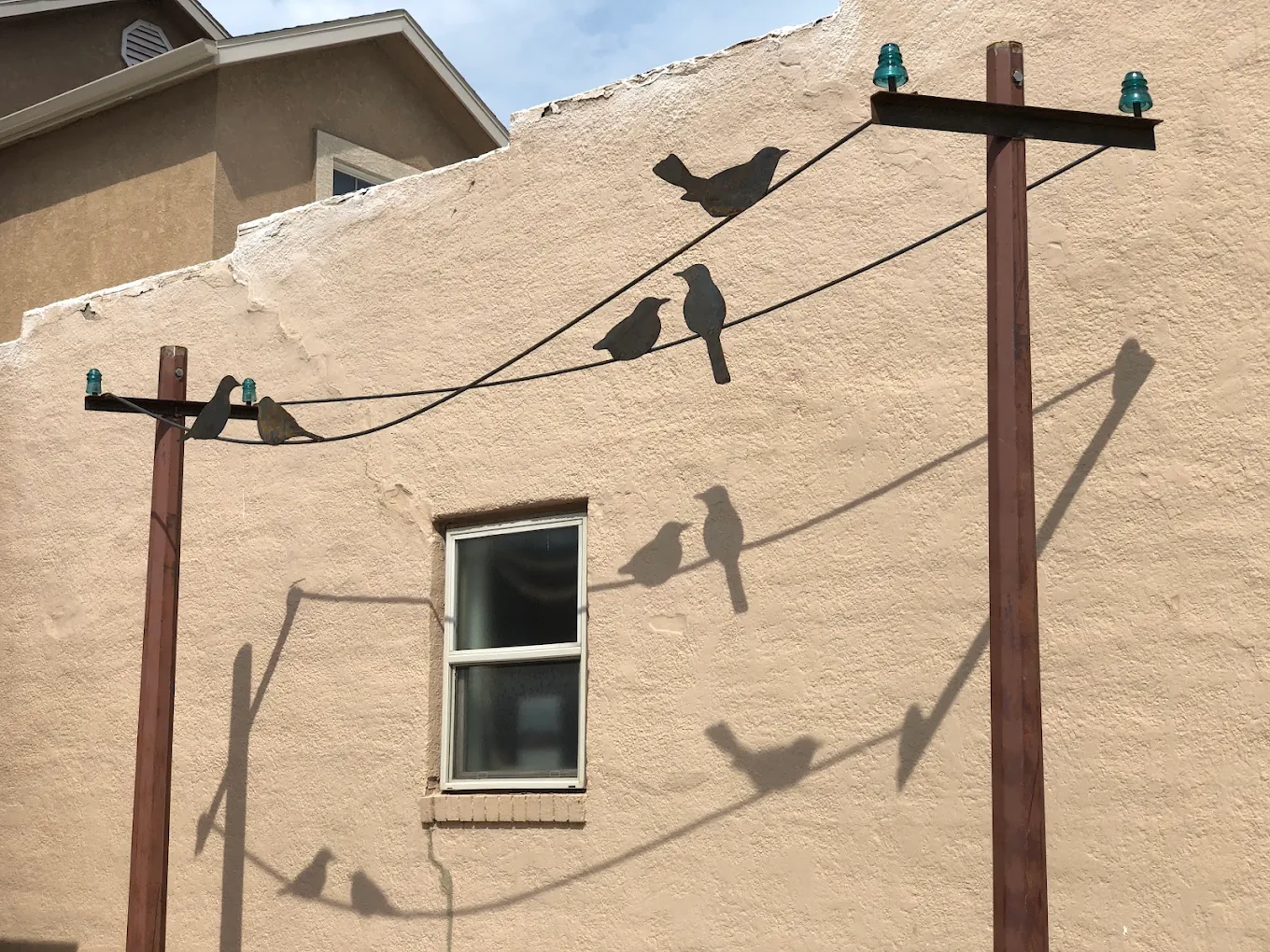 Bird silhouettes on overhead wires decorating the sunny exterior wall
